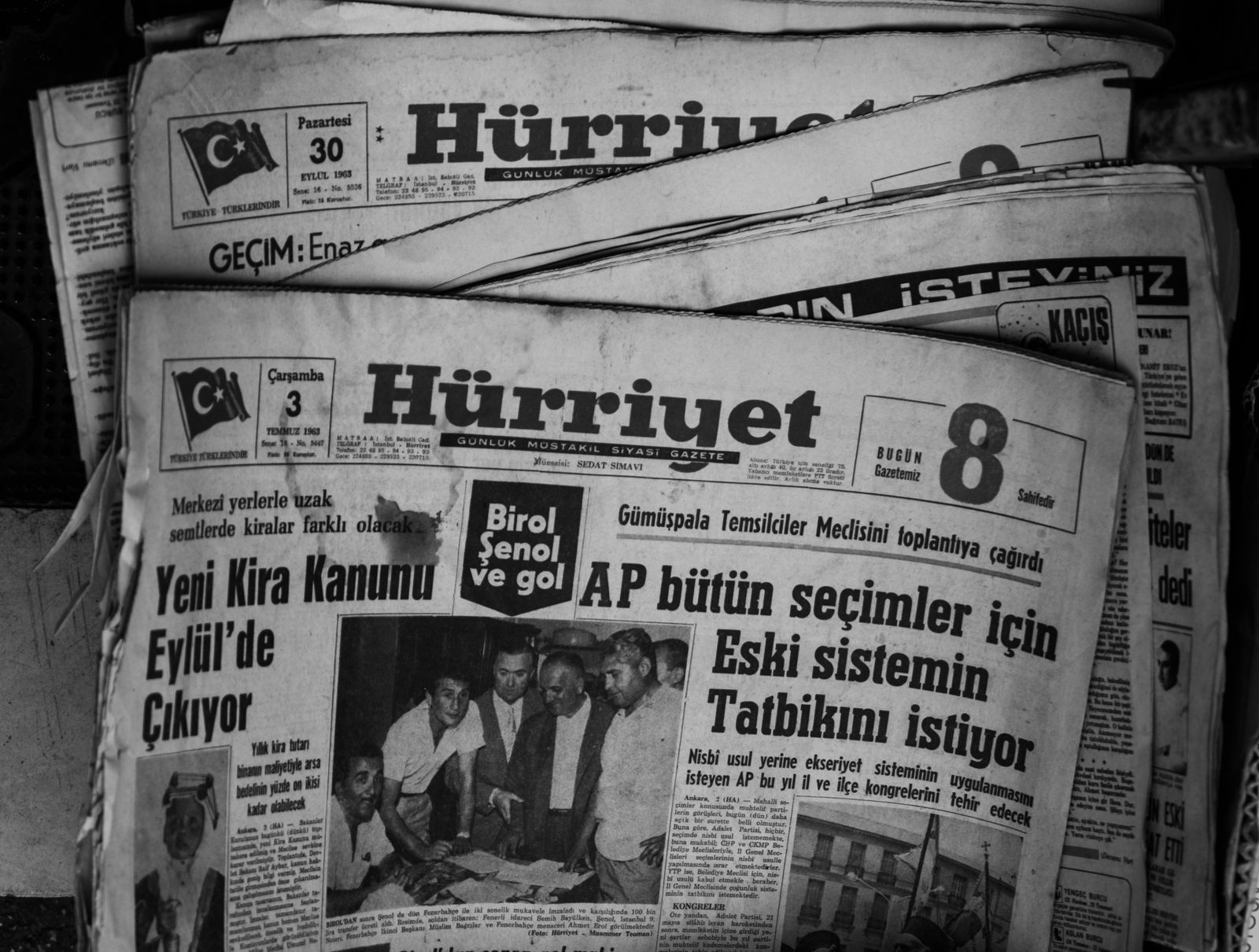Image en noir et blanc de journaux turcs empilés, montrant les gros titres de 1963.